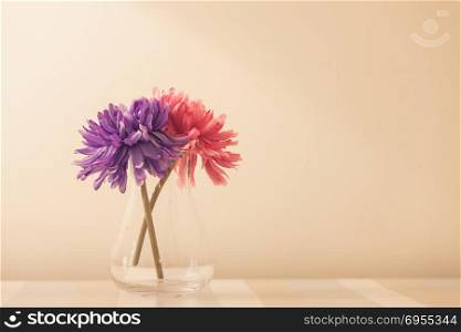 flowers in a vase on wooden table over white wall