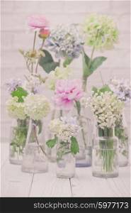Flowers in bottles over white wall, vintage styled