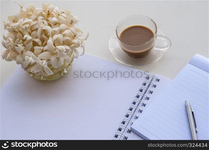 Flowers, pens and coffee mugs On a white note book