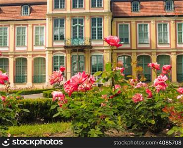 flowers pink roses and abbots palace landmark in gdansk danzig polish city oliva park. historical building residence house.