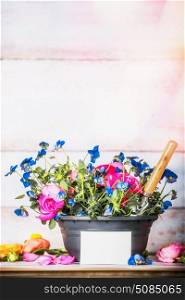 Flowers pot with shovel and blank white card on gardening table at white wooden background, front view