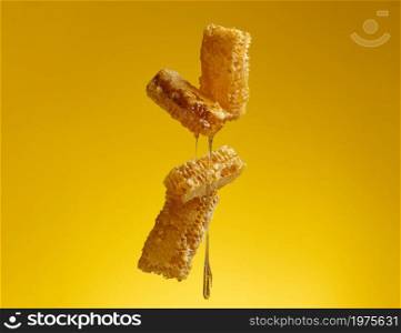 flowing honey over honeycomb on yellow background