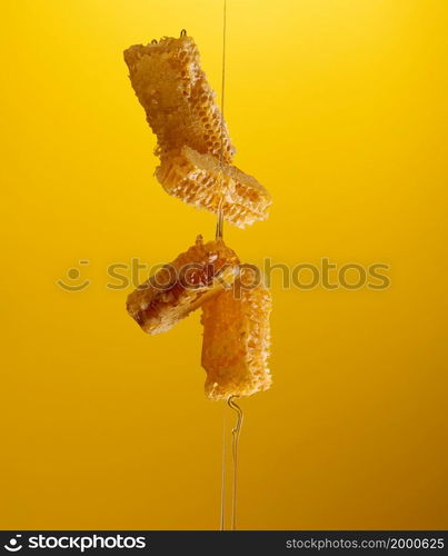 flowing honey over honeycomb on yellow background