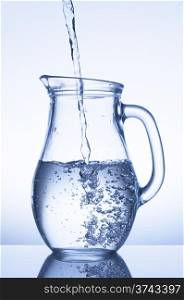 Flowing water in a jug on blue background