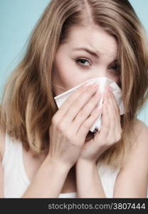 Flu cold or allergy symptom. Sick woman girl sneezing in tissue on blue. Health care.