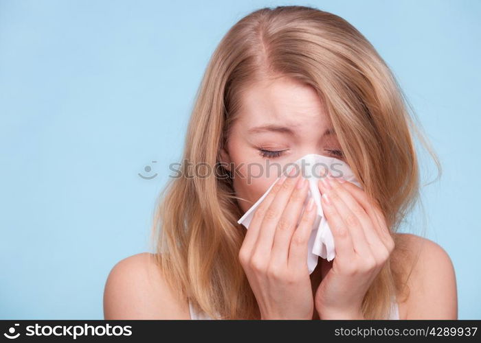 Flu cold or allergy symptom. Sick young woman girl sneezing in tissue on blue. Health care. Studio shot.