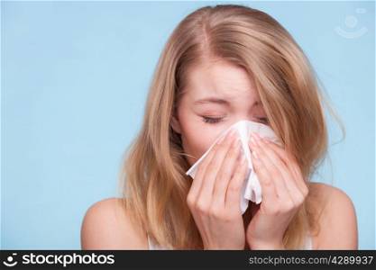 Flu cold or allergy symptom. Sick young woman girl sneezing in tissue on blue. Health care. Studio shot.