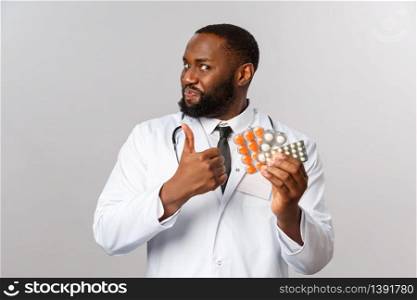 Flu, disease, healthcare and medicine concept. Portrait of handsome funny doctor assure this pills work, show thumb-up recommend drugstore with best prices on pills and medication.. Flu, disease, healthcare and medicine concept. Portrait of handsome funny doctor assure this pills work, show thumb-up recommend drugstore with best prices on pills and medication