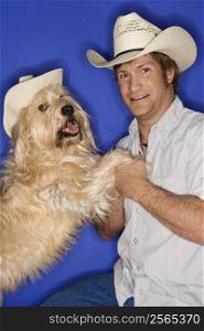 Fluffy brown dog and male Caucasian young adult wearing cowboy hats.