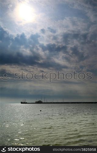 fluffy clouds blue sky above a surface of the sea and pier, Poland Baltic