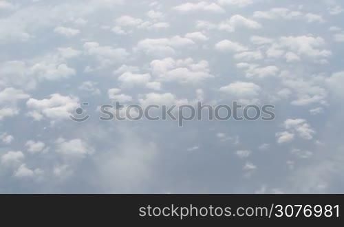 Fluffy clouds in the blue sky. View from the window of an airplane flying in the clouds at daytime.