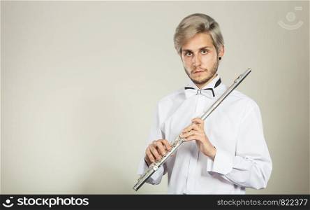 Flute music playing professional male flutist musician performer. Young elegant stylish man with instrument. Flute music playing flutist musician performer
