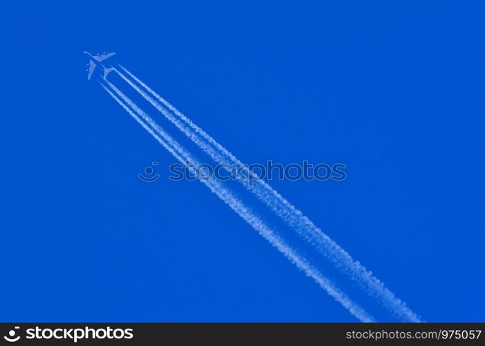 Flying aeroplane with leaving white trails on a blue sky