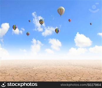Flying aerostats. Colorful balloons flying high in blue sky above desert