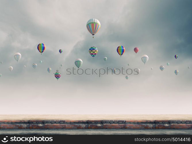 Flying aerostats. Colorful balloons flying high in grey sky