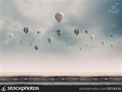Flying aerostats. Colorful balloons flying high in grey sky