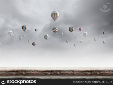 Flying aerostats. Colorful balloons flying high in grey sky