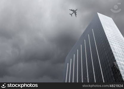 Flying airplane. Bottom view of airplane flying above skyscrapers