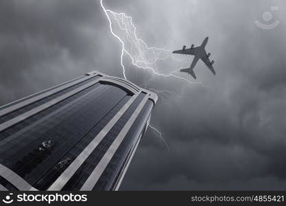 Flying airplane. Bottom view of airplane flying above skyscrapers