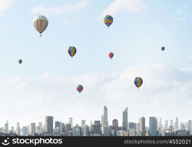 Flying balloons. Colorful aerostats flying in clear sky above modern city