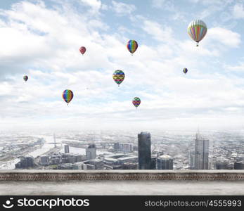 Flying balloons. Colorful aerostats flying in clear sky above modern city