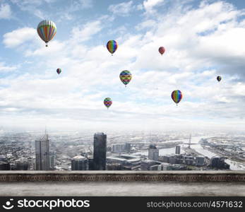 Flying balloons. Colorful aerostats flying in clear sky above modern city