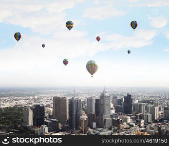 Flying balloons. Colorful aerostats flying in clear sky above modern city