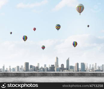 Flying balloons. Colorful aerostats flying in clear sky above modern city