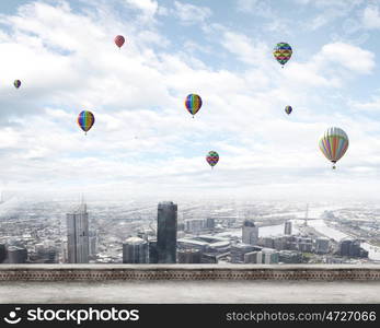 Flying balloons. Colorful aerostats flying in clear sky above modern city