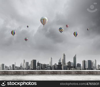 Flying balloons. Colorful aerostats flying in clear sky above modern city