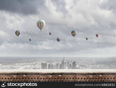 Flying balloons. Colorful aerostats flying in clear sky above modern city