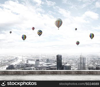 Flying balloons. Colorful aerostats flying in clear sky above modern city