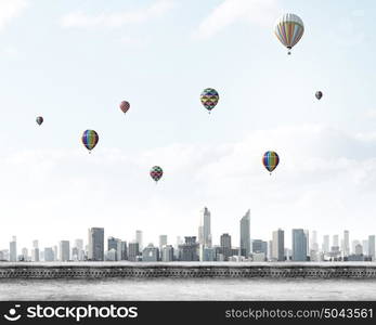 Flying balloons. Colorful aerostats flying in clear sky above modern city