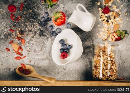 Flying breakfast against grey wall. Granola and berries falling or flying in motion.. Flying breakfast against grey wall. Healthy eating concept