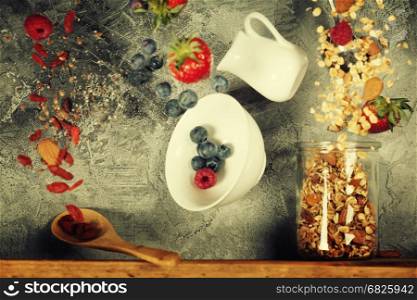 Flying breakfast against grey wall. Granola and berries falling or flying in motion.