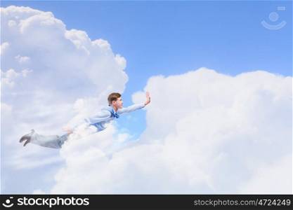 Flying businessman. Young businessman superhero flying high in sky