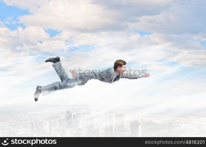 Flying businessman. Young businessman superhero flying high in sky