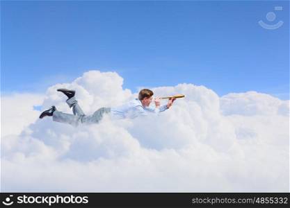 Flying businessman. Young man flying high in sky and looking in spyglass