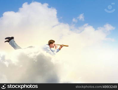 Flying businessman. Young man flying high in sky and looking in spyglass