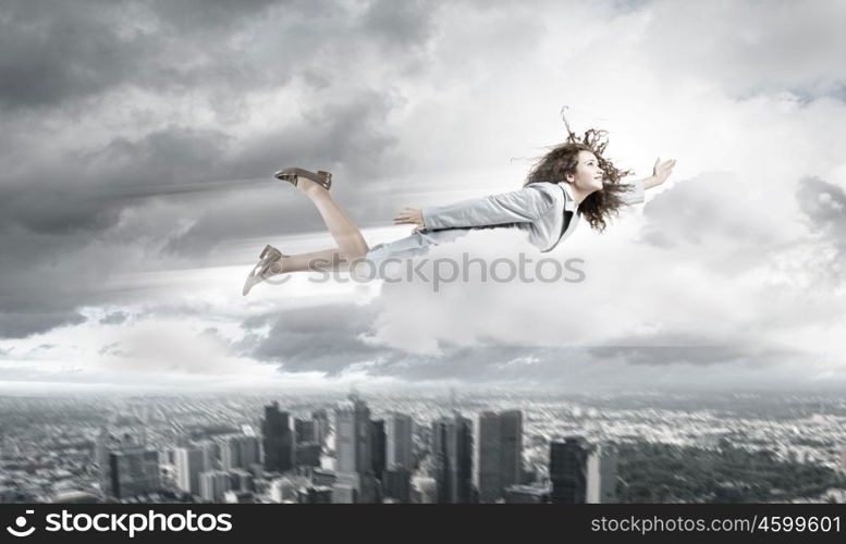 Flying businesswoman. Young determined businesswoman flying high in sky