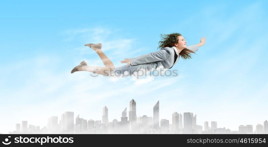 Flying businesswoman. Young determined businesswoman flying high in sky