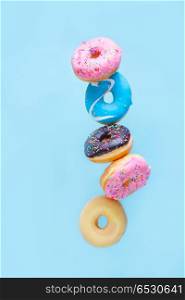 flying doughnuts on blue. flying doughnuts - balancing tower of multicolored sweet donuts with sprinkles on blue background