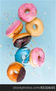 flying doughnuts on blue. flying doughnuts scene - mix of multicolored sweet donuts with sprinkel on blue background