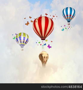 Flying elephant. Sunny image of elephant flying in sky on aerostat