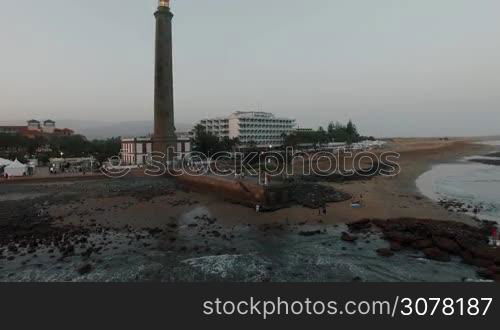 Flying from the coast with resort and lighthouse in the evening. Maspalomas, Gran Canaria