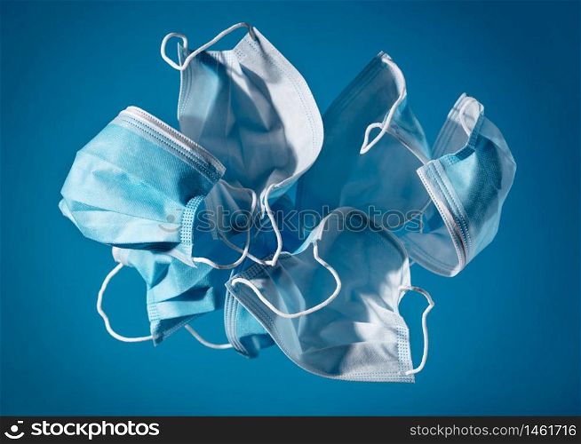 flying masks on blue background. The most sought after coronavirus covid-19 protection item in worldwide. Stop SARSCoV, virus 2020, COVID-19.. Flying masks on blue background - Face mask protection, virus, flu, coronavirus, COVID-19. Medical equipment.