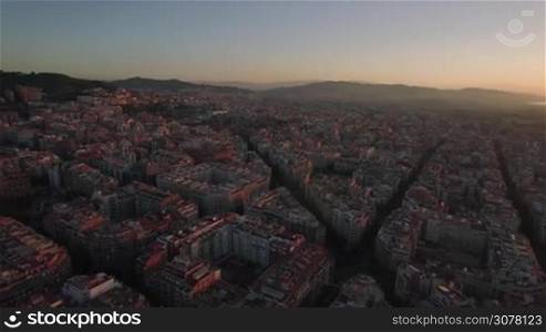 Flying over Barcelona at sunset, Spain. Streets and houses in warm light of evening sun
