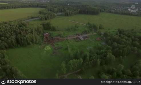 Flying over countryside with old ruins and highway with car traffic running through the fields and woods near the villages, Russia
