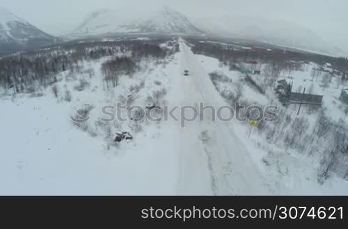 Flying over the car driving along snowy road and parking by the hotel of ski centre Ruka