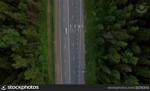 Flying over the road in the countryside. Cars driving along the village, woods and fields. Russia